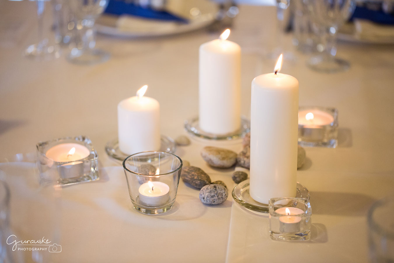 Stalo dekoravimas balta žvakė akmenukai